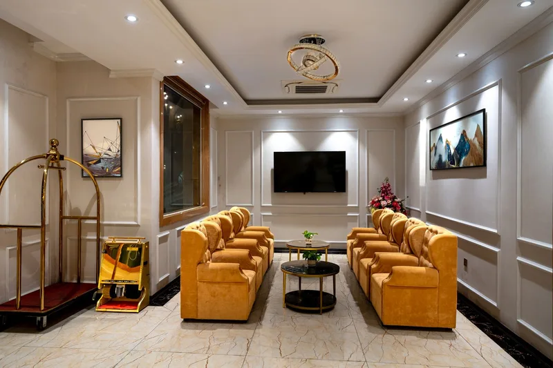 A hotel lounge with golden armchairs and a wall-mounted display